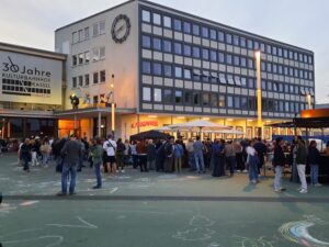 Viele Menschen stehen auf dem abendlichen Bahnhofsvorplatz des KulturBahnhofes