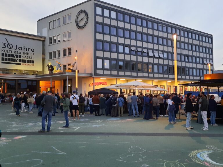 Viele Menschen stehen auf dem abendlichen Bahnhofsvorplatz des KulturBahnhofes